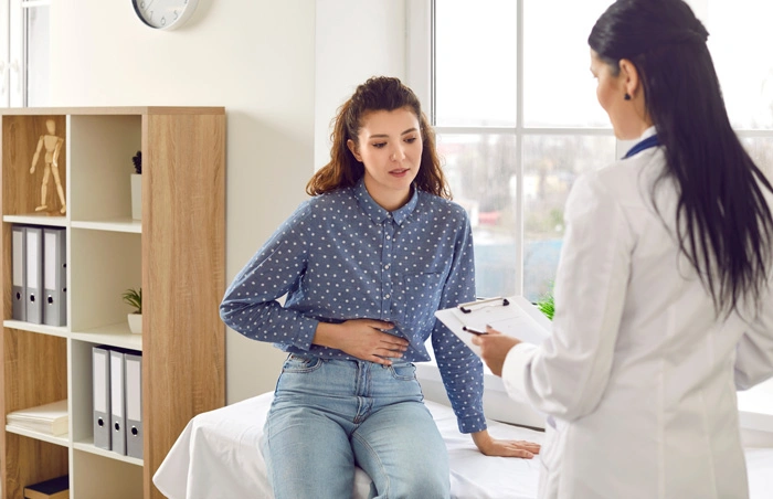 Female medical specialist consults young female patient who complains of abdominal pain