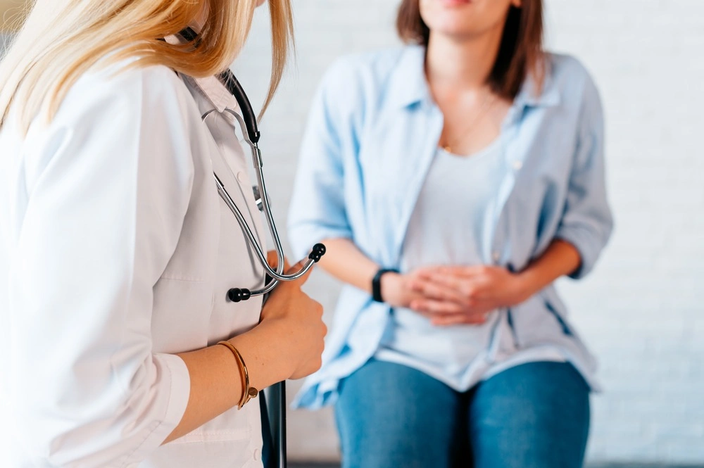 a woman in consultation with a doctor with abdominal pain