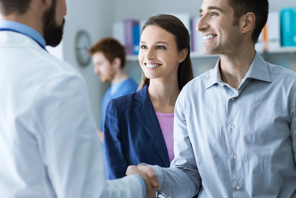 Couple shaking hands with a doctor