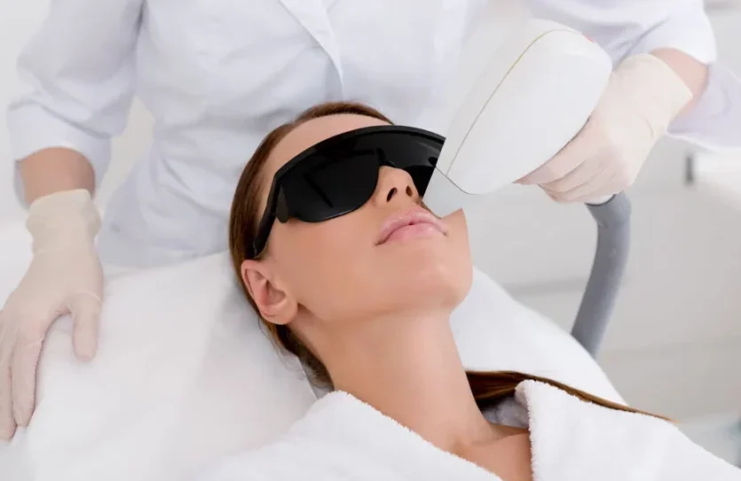 partial view of young woman receiving laser hair removal epilation on face in salon