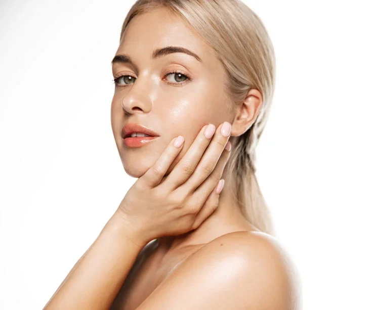 Young blond woman touching soft, glowing and clean face cheek,