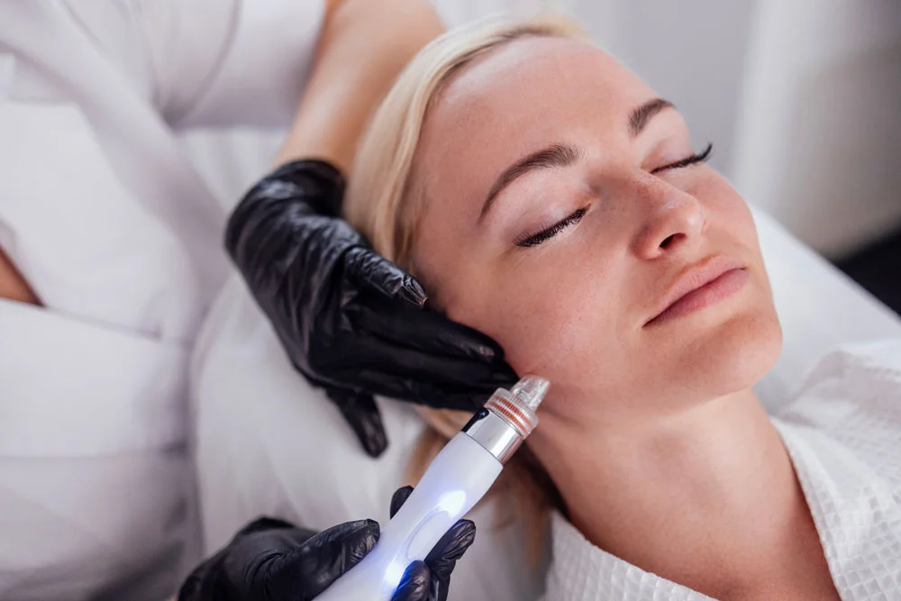 Young woman lies with her eyes closed during hardware moisturizing of the facial skin.